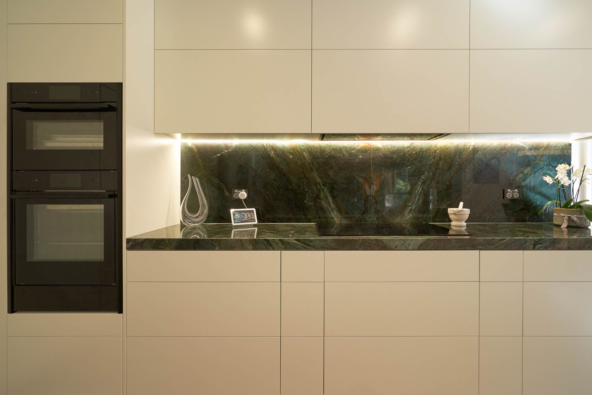 Flat white kitchen with green stone countertop and custom cabinetry