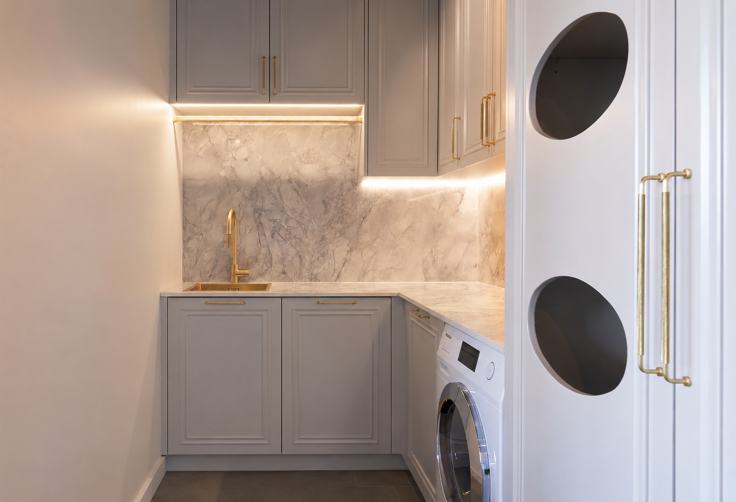 Custom laundry joinery with stone surfaces by Renolux Sydney